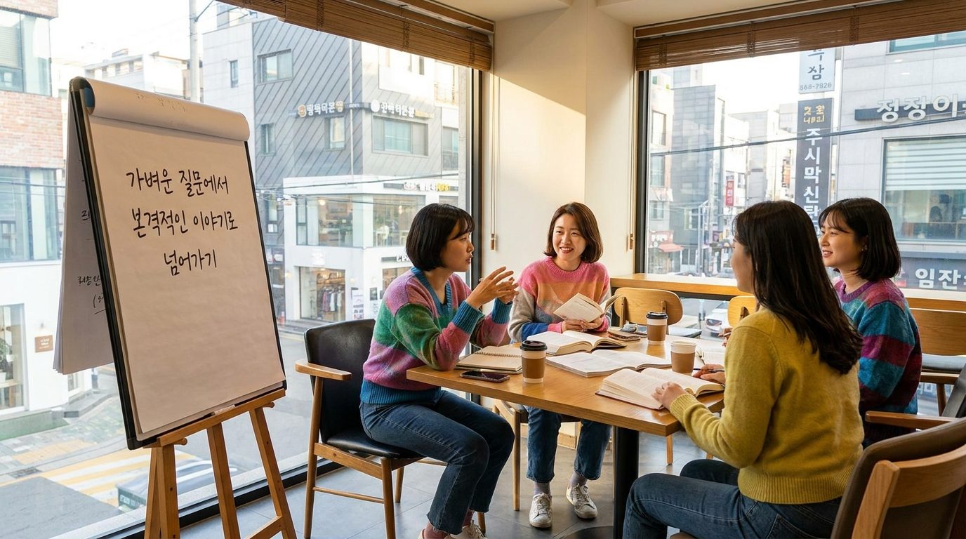 가벼운 아이스브레이킹 질문에서 본격적인 책 이야기로 자연스럽게 넘어가는 과정을 나타내는 한국 여성들의 북클럽 모임 장면, 창가 자연광 아래 책과 노트가 놓인 테이블에 둘러앉아 있다.